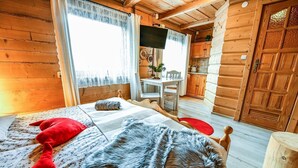 A cozy log cabin bedroom with a bed, a television, and a wooden door. - Willa Bachledowka (Zakopane)