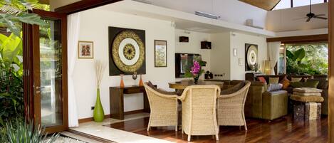 A spacious living area with a dining table, wicker chairs, and a sofa.