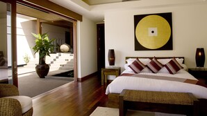A modern hotel room with a large bed, a potted plant, and a view of the outside.