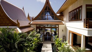 A traditional Thai house with a central courtyard, wooden architecture, and lush greenery.