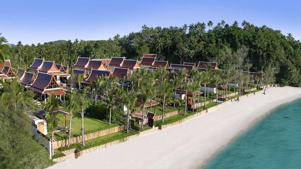 A resort with beachside villas, a sandy beach, and a clear view of the ocean.