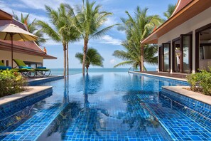 Una piscina al aire libre, sombrillas, sillones reclinables de piscina