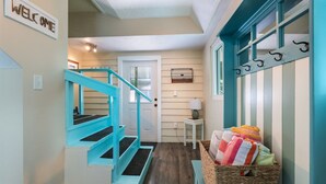 Un escalier avec des rampes de couleur turquoise menant à une porte sur laquelle est inscrit le mot « PLAGE ».