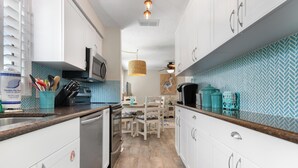 Une cuisine moderne avec des meubles blancs, un four à micro-ondes et un coin repas comprenant une table et des chaises.