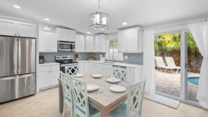 A modern kitchen with white cabinets, stainless steel appliances, and a dining area with a table set for four.