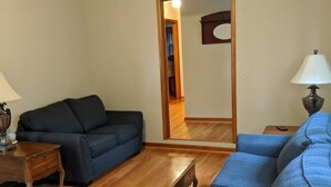 A living room with a dark blue sofa, a wooden coffee table, and a lamp on a side table. - s1. Beautiful home in historic Scottsboro w/ pool (Scottsboro)