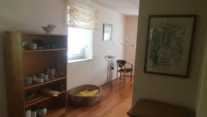 A room with a wooden floor, a bookshelf, a window with curtains, a floor lamp, a chair, and a framed picture on the wall. - Reizvolles Domizil (Vollmersweiler)