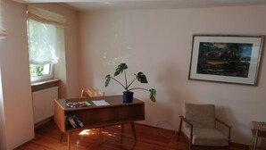 A room with a wooden floor, a desk with a plant, a chair, and a framed picture on the wall. - Reizvolles Domizil (Vollmersweiler)
