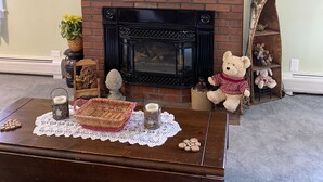 A living room with a brick fireplace, a television mounted above it, and a coffee table with decorative items. - Just 3 miles Cooperstown, Hall of Fame, 2.5 miles to Baseball Dreams Park. (Cooperstown)