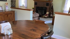 A spacious living room with a large wooden dining table, comfortable seating, a fireplace, and a television mounted on the wall. - Just 3 miles Cooperstown, Hall of Fame, 2.5 miles to Baseball Dreams Park. (Cooperstown)