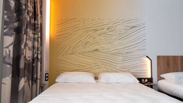 Une chambre d’hôtel dotée d’un grand lit, de deux tables de chevet et d’un mur au revêtement texturé original.