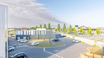 Een parkeerplaats met auto's, een gebouw met een modern ontwerp en een heldere lucht.