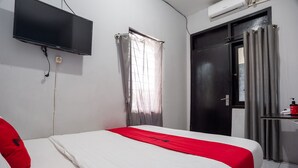 A hotel room with a bed, a TV mounted on the wall, a door, and a window with curtains. - RedDoorz Syariah near Margonda Raya (Depok)