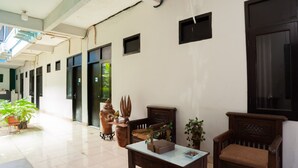 A spacious hallway with tiled flooring, a wooden bench, a table, and potted plants. - RedDoorz Syariah near Margonda Raya (Depok)