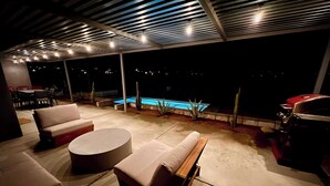 An outdoor patio with a pool, lounge chairs, and a grill area.