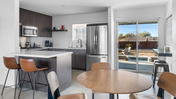 A modern kitchen with a large island, bar stools, and a dining table.