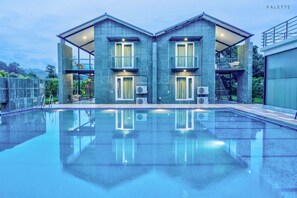 A modern building with a swimming pool in front.