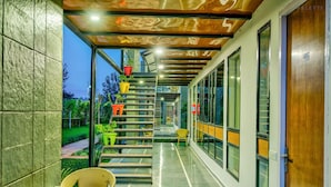 A modern corridor with a glass wall, a staircase, and outdoor seating. - The Cloyster Resort and Spa (Ramnagar)