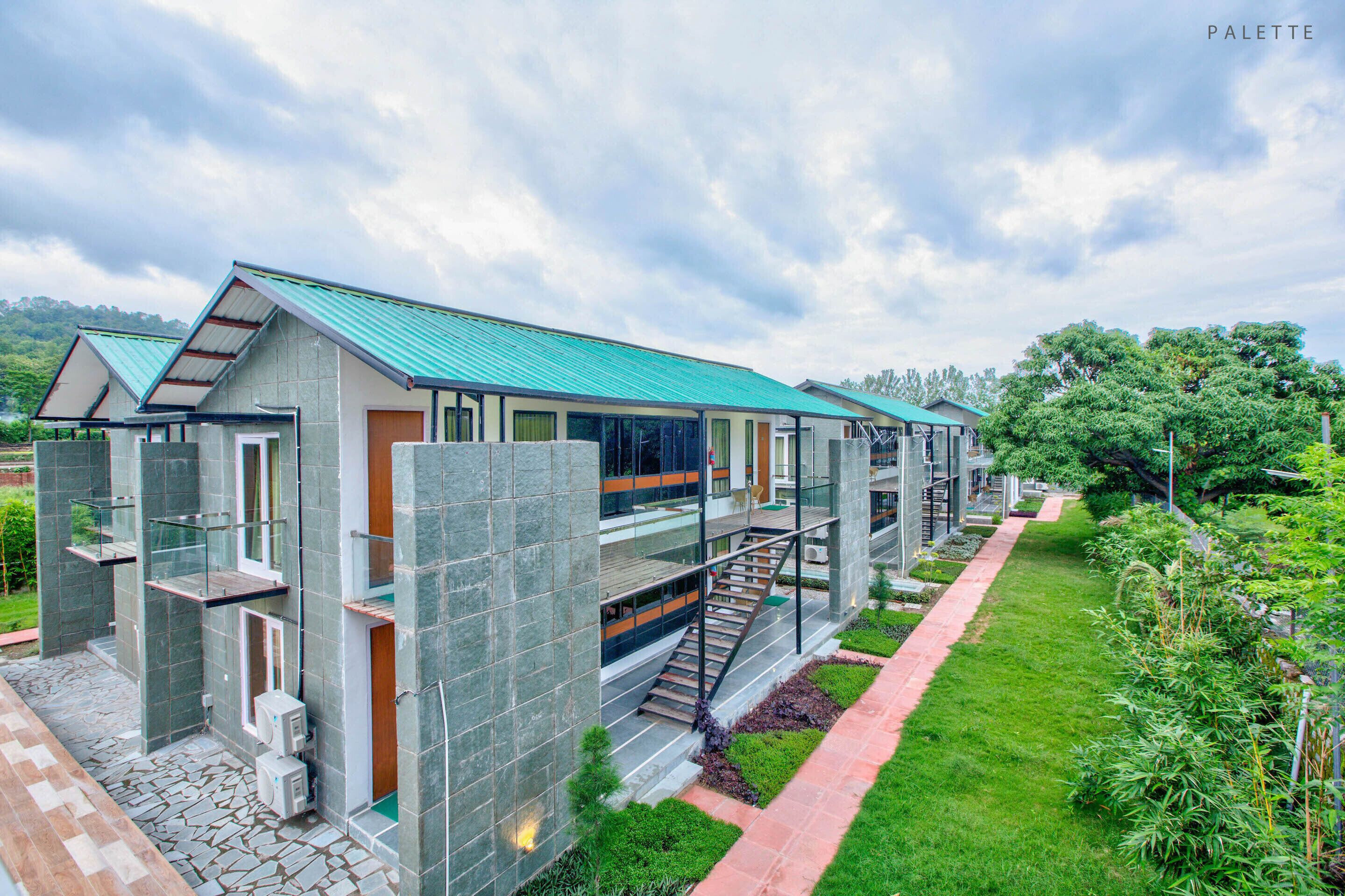 A modern hotel with a green roof, multiple floors, and a well-maintained garden.