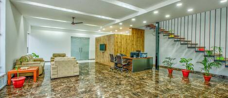 A spacious lobby with a reception desk, seating area, and a staircase.