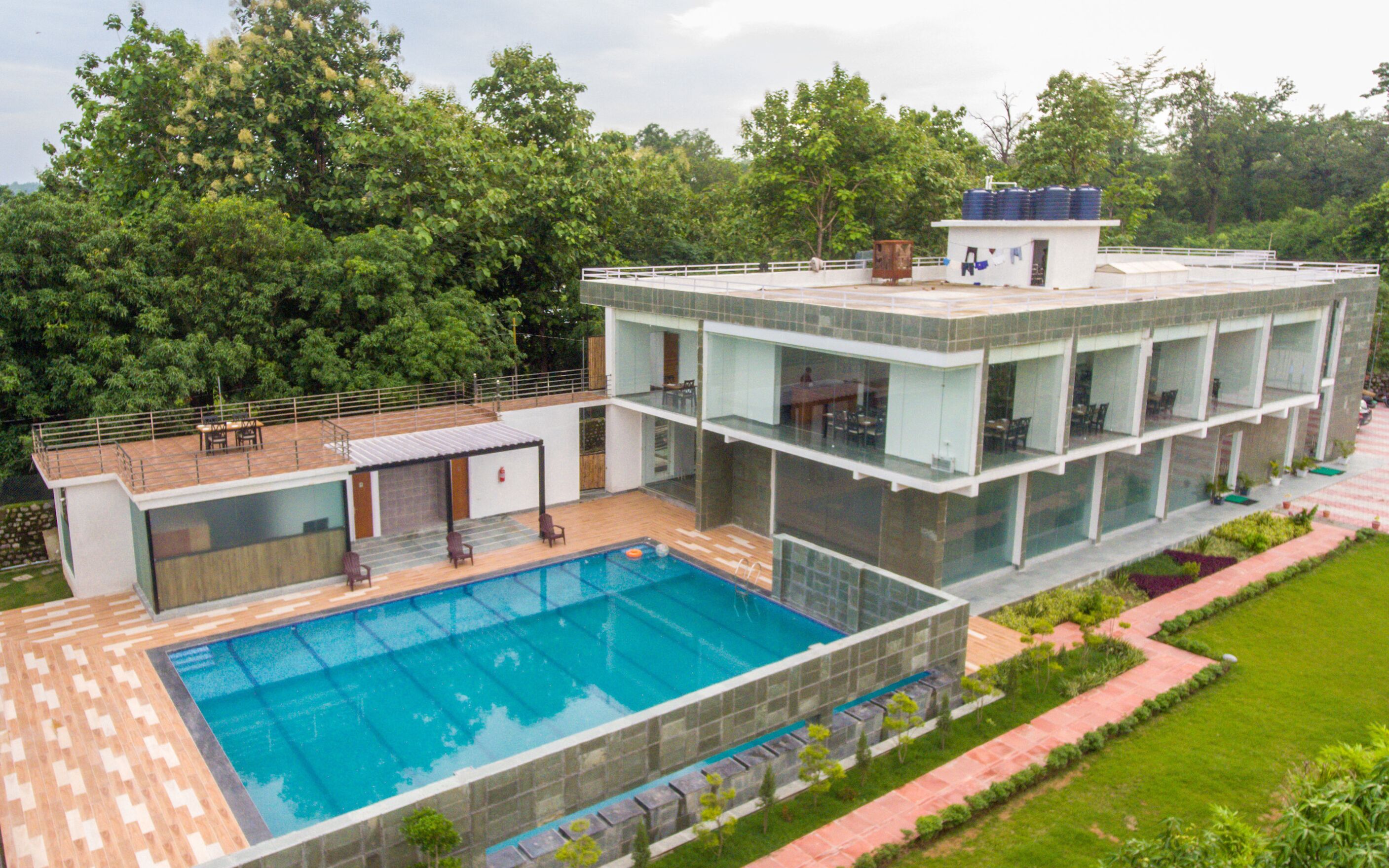 A modern building with a swimming pool, multiple balconies, and a garden area.