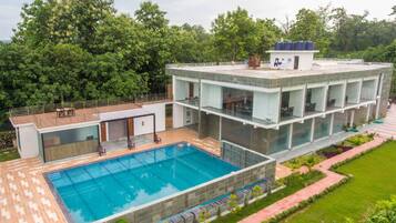 A modern building with a swimming pool, multiple balconies, and a garden area.