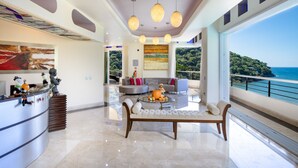 A spacious living area with a modern sofa, a coffee table with a pumpkin centerpiece, and a large window offering a view of the sea. - Fully Staffed, Beach frontage Luxury Villa (Boca de Tomatlán)