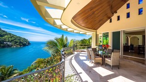 A balcony with a view of the sea, wicker furniture, and a dining area with a table and chairs. - Fully Staffed, Beach frontage Luxury Villa (Boca de Tomatlán)