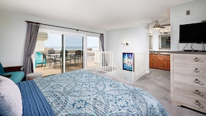 Ein Schlafzimmer mit einem großen Bett, einem Fernseher, einem Balkon mit Blick und einer Küchenzeile.