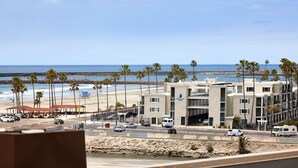 Ein Hotel an der Küste mit Blick auf den Strand, mehreren Etagen und einem Parkplatz mit einigen Fahrzeugen.