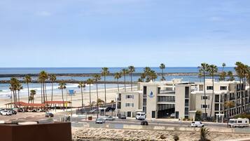 A coastal hotel with a beach view, multiple floors, and a parking area with several vehicles.