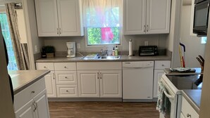 A compact kitchen with white cabinets, a built-in oven, a microwave, and a sink. - Cardinal  Cottage 55 Patton Cemetery Road (Swannanoa)