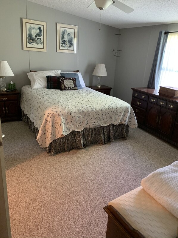 A bedroom with a bed, two nightstands, a dresser, and two framed artworks on the wall.