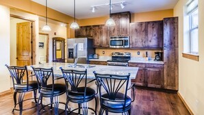 Cucina con mobili in legno, frigorifero in acciaio inossidabile, forno a microonde e una grande isola con sgabelli da bar.