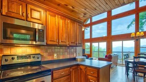 Une cuisine dotée de meubles en bois, d’appareils électroménagers en acier inoxydable et d’une grande fenêtre donnant sur un paysage magnifique.