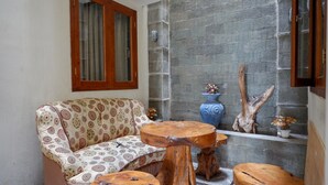 A cozy room with a patterned sofa, wooden stools, and a stone wall.
