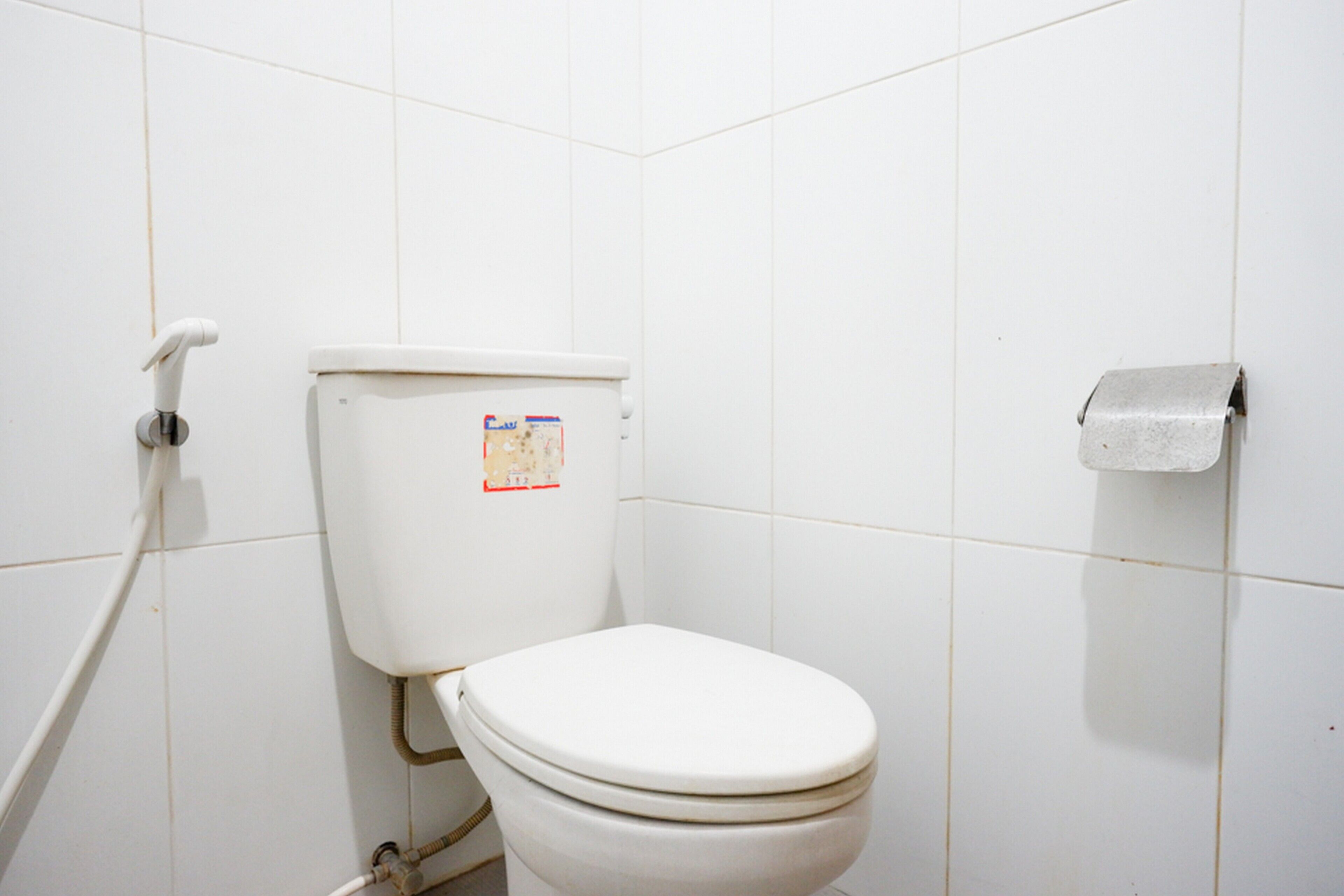 Een wit toilet met een papieren handdoekhouder aan de muur.