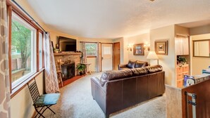 Ein gemütliches Wohnzimmer mit Kamin, Ledersofa und Essbereich mit Tisch und Stühlen.