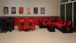 A modern living room with a red sofa, black and red cushions, a red dining table with chairs, and motivational posters on the wall. - Reddoorz @ Sindangbarang Bogor (Bogor)