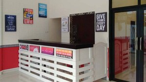 A reception desk with motivational posters on the wall, a glass door, and a red wall to the left. - Reddoorz @ Sindangbarang Bogor (Bogor)
