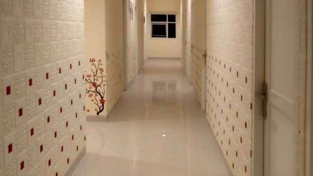 A hallway with white walls and a tiled floor, leading to a door at the end. - Reddoorz @ Sindangbarang Bogor (Bogor)