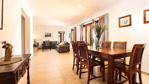 A dining area with a wooden table and chairs, a sofa, and a vase with flowers. - Can MARES. Stunning villa. A great choice (Pollensa)
