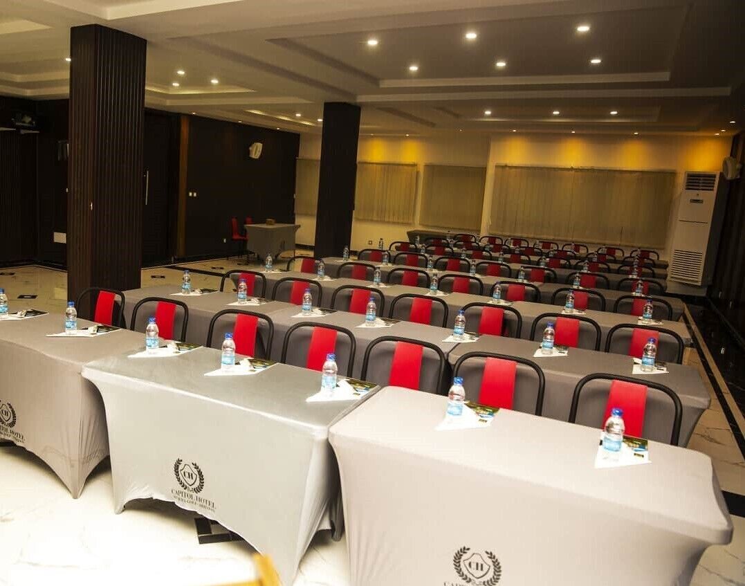 A conference room with rows of tables and chairs, each with a water bottle and a name tag.
