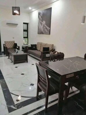 A modern living room with a sofa, chairs, a coffee table, and a dining table. - Hotel Capitol Abidjan (Abidjan)