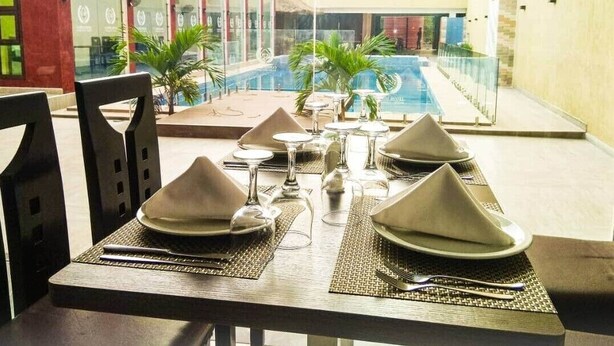 A dining table set for four with a view of a swimming pool and a building in the background.