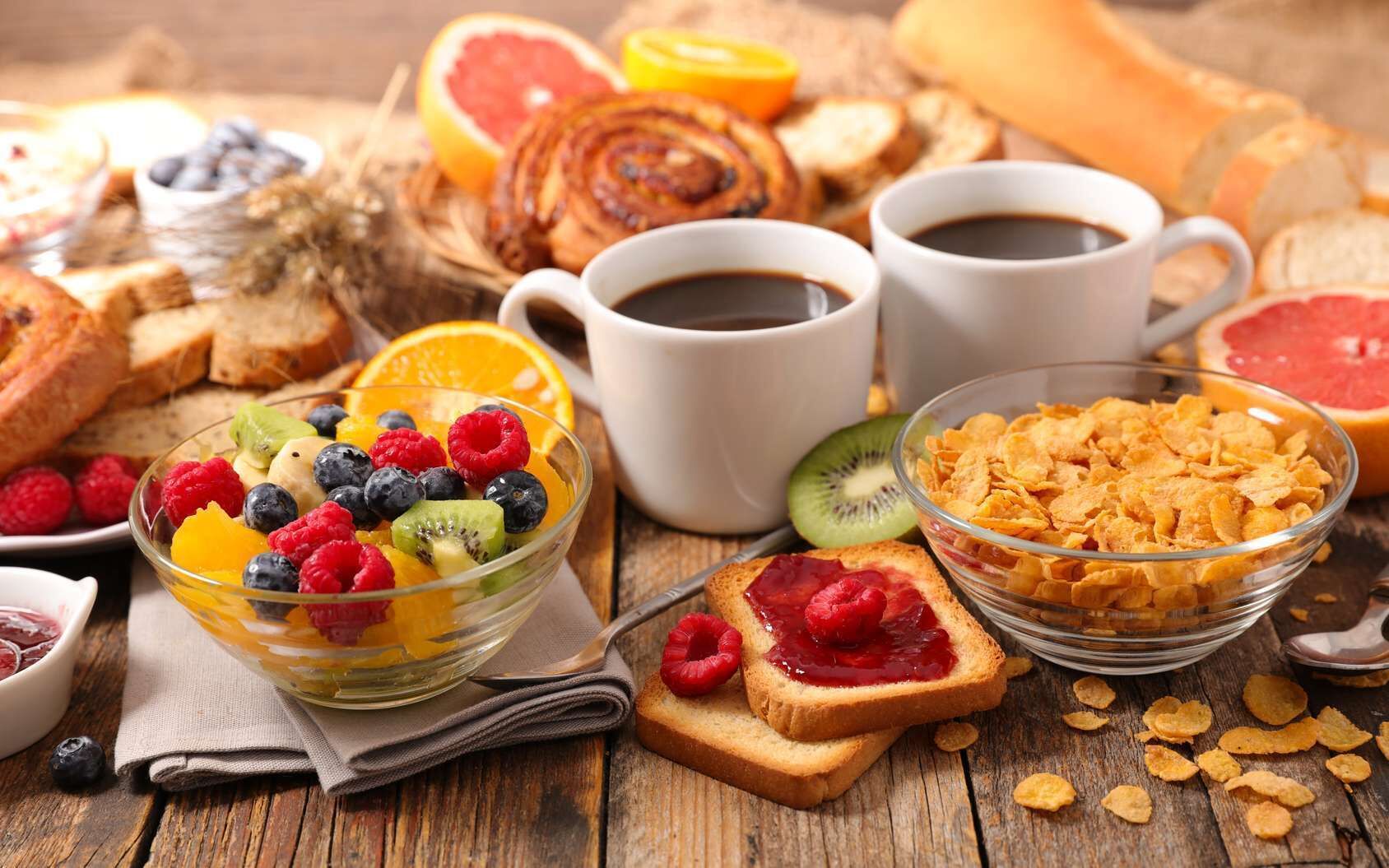 A breakfast setting with toast, cereal, fruit, and coffee.