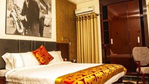 A hotel room with a large bed, a chair, a wardrobe, and a wall-mounted air conditioner.