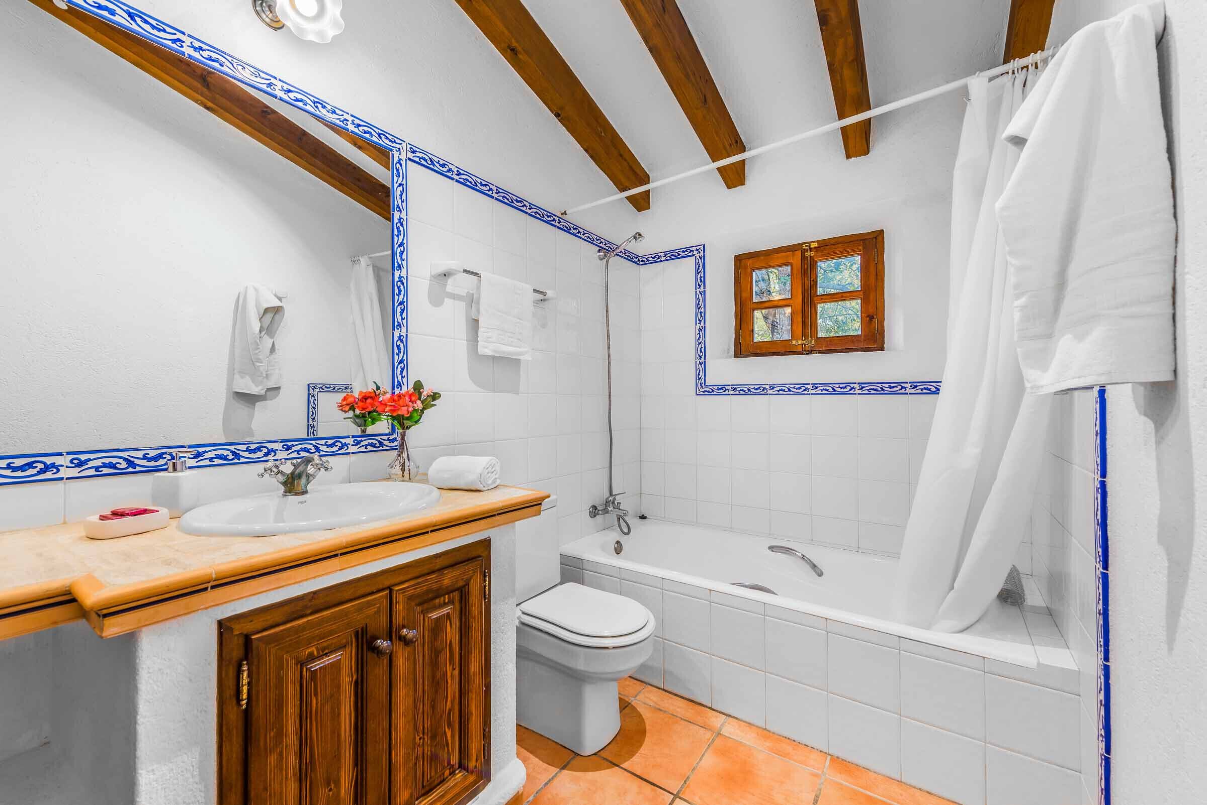 A bathroom with a wooden vanity, white tiles, a bathtub, and a shower curtain.