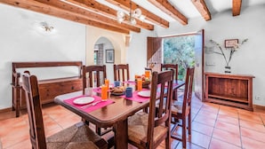 A dining area with wooden furniture, a table set with plates, glasses, and a fruit bowl. - TOMAS. Pretty and classical  villa close to Cala San Vicente (Cala San Vicente)