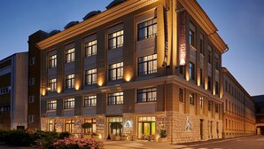 Un hotel de varios pisos con un diseño arquitectónico clásico, con amplias ventanas y una entrada bien iluminada.